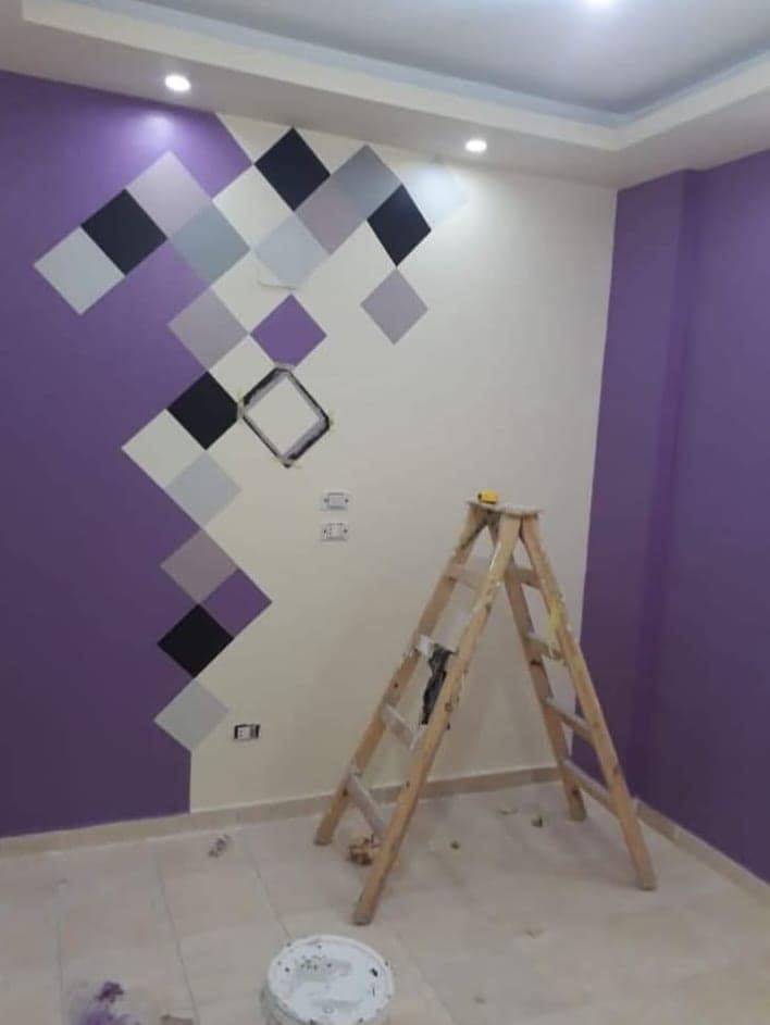 Painter's ladder and dust sheet in a Visakhapatnam bedroom, a purple and grey diamond wall pattern half finished
