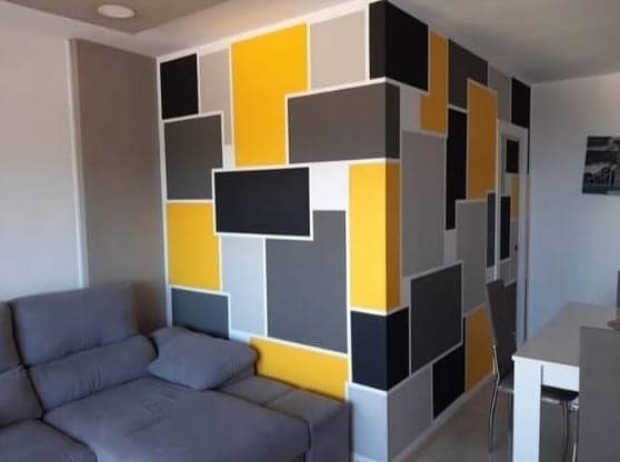 Living room wall painted in a yellow, grey and black geometric block pattern, Visakhapatnam