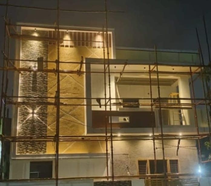 Residential building under construction in Visakhapatnam at night, bamboo scaffolding in place and the elevation lit
